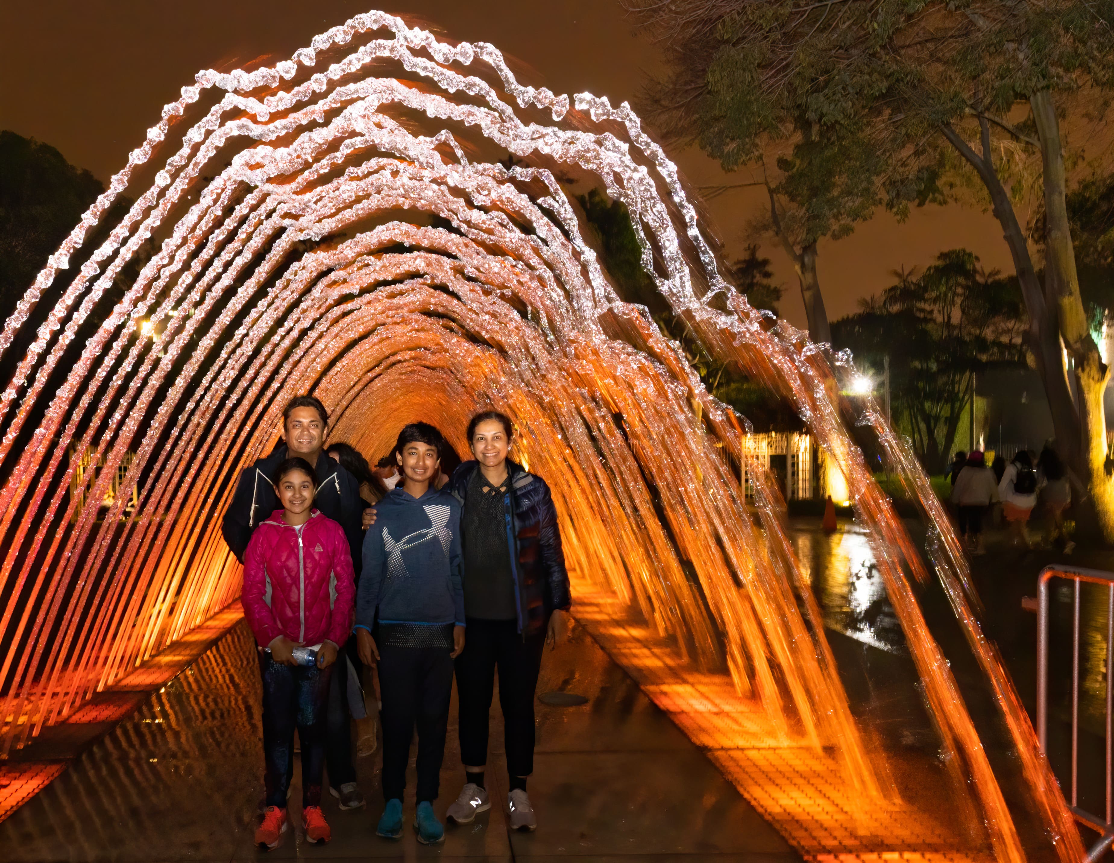 Family underneath colorful water arch in Spain